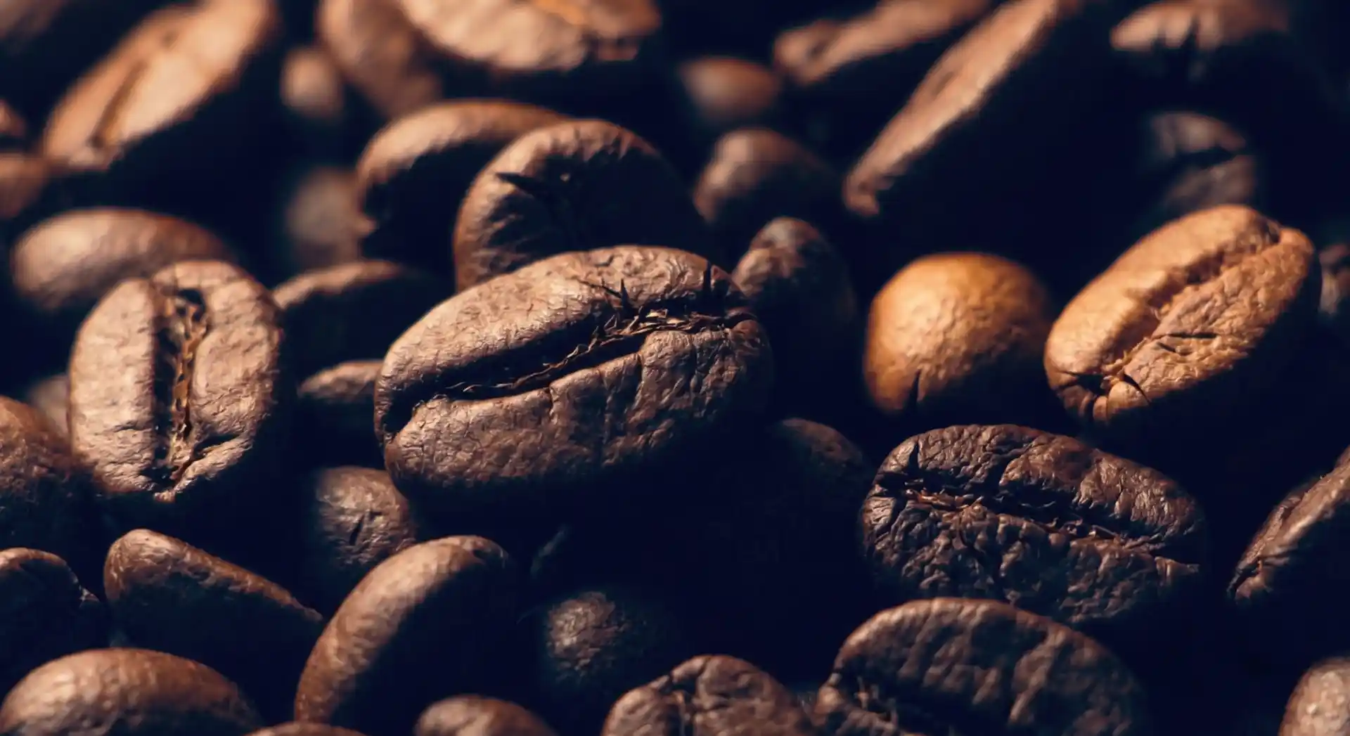 Extreme Makroaufnahme von dunkel gerösteten Espresso-Kaffeebohnen in stimmungsvollem Licht mit geringer Schärfentiefe.