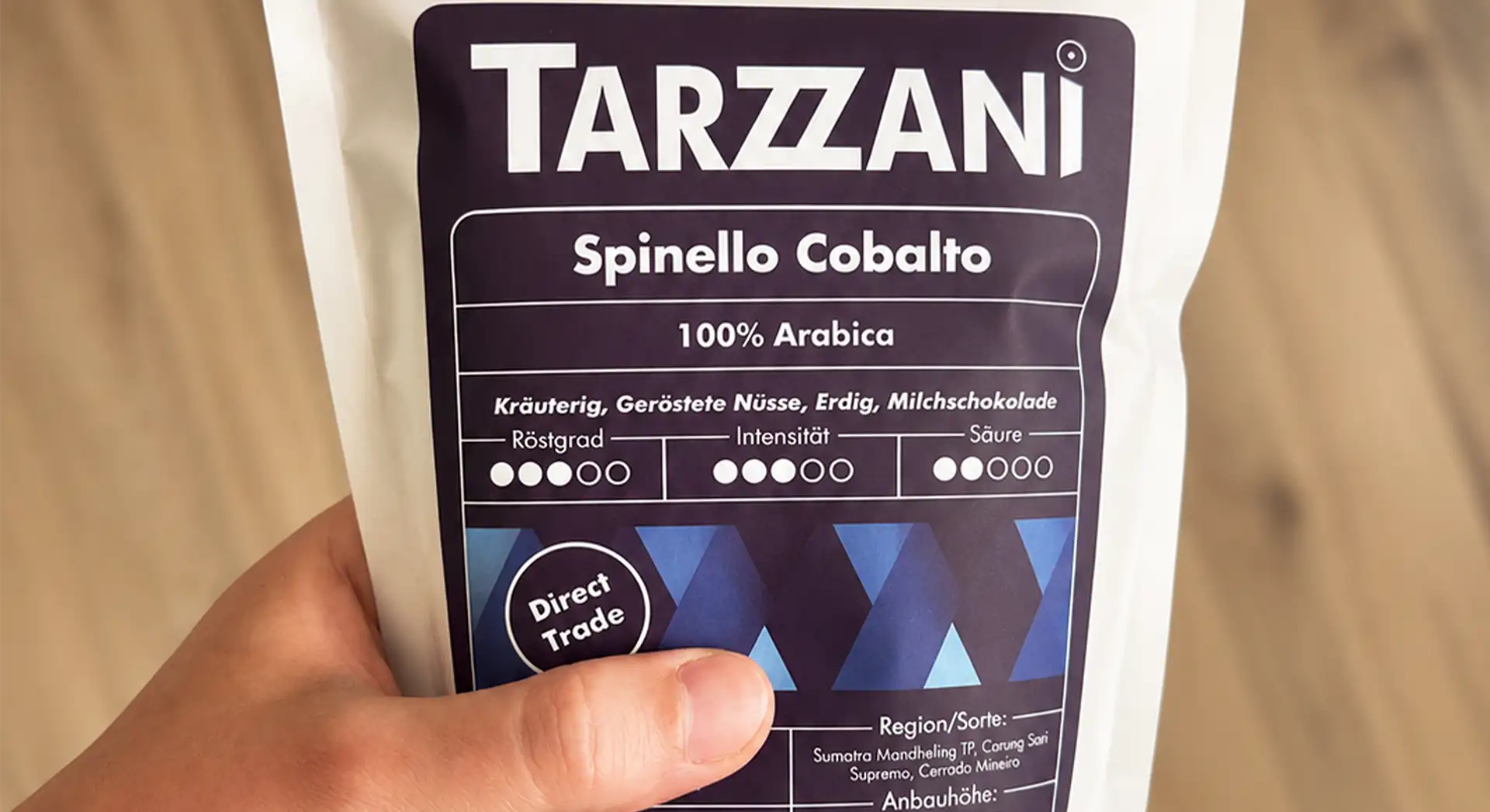 Hand hält eine weiße Tarzzani Kaffeetüte der Sorte Spinello Cobalto mit detaillierten Etikett-Angaben zu Geschmack, Röstgrad und Herkunft.